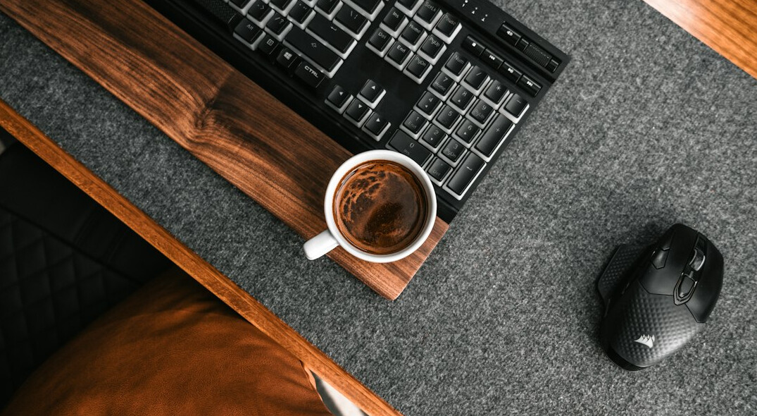Overhead view of a desk with a laptop showing programming code, notebook, and coffee cup